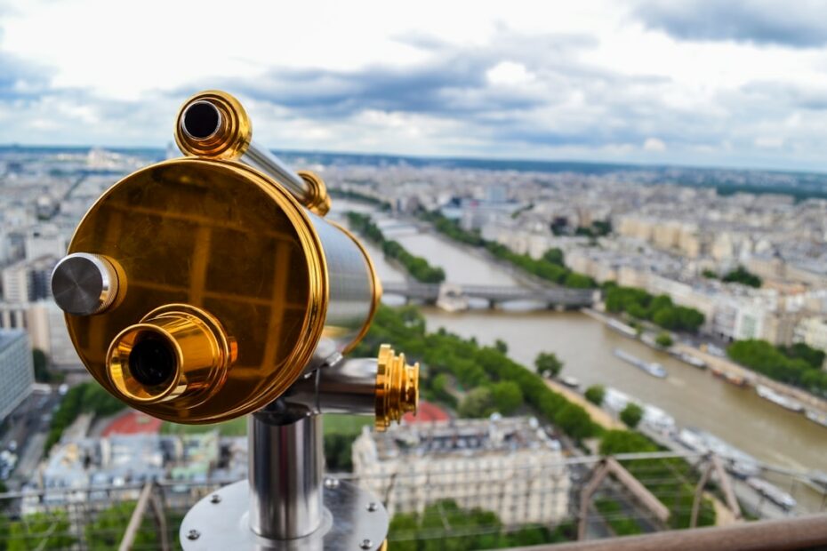 Golden telescope overlooks a sprawling city with river.